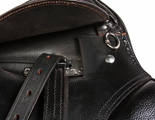 Close-up of a black leather horse saddle with straps and metal rings.