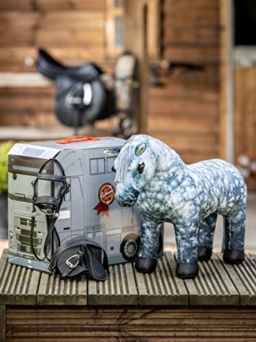 Plush horse toy next to a toy stable with equestrian gear.